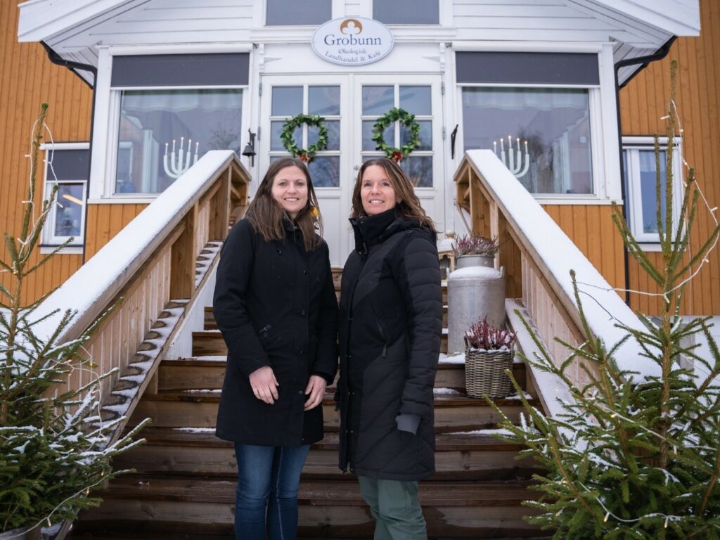 To kvinner står utendørs på en trapp opp til et hus